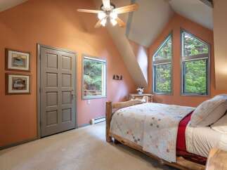 Experience rustic charm in this cozy bedroom featuring a unique log bed and a tranquil forest view.