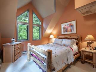 Experience rustic charm in this cozy bedroom, featuring a unique log bed and a charming quilt.