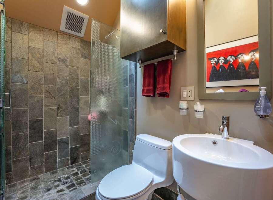 Experience modern luxury in this stylish bathroom, featuring a spacious walk-in shower with slate tile accents and a sleek glass enclosure.