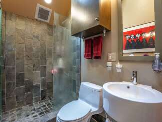 Experience modern luxury in this stylish bathroom, featuring a spacious walk-in shower with slate tile accents and a sleek glass enclosure.