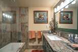 This bathroom features a luxurious bathtub with slate tile surround, complemented by a spacious vanity with a granite countertop and a modern undermount sink.