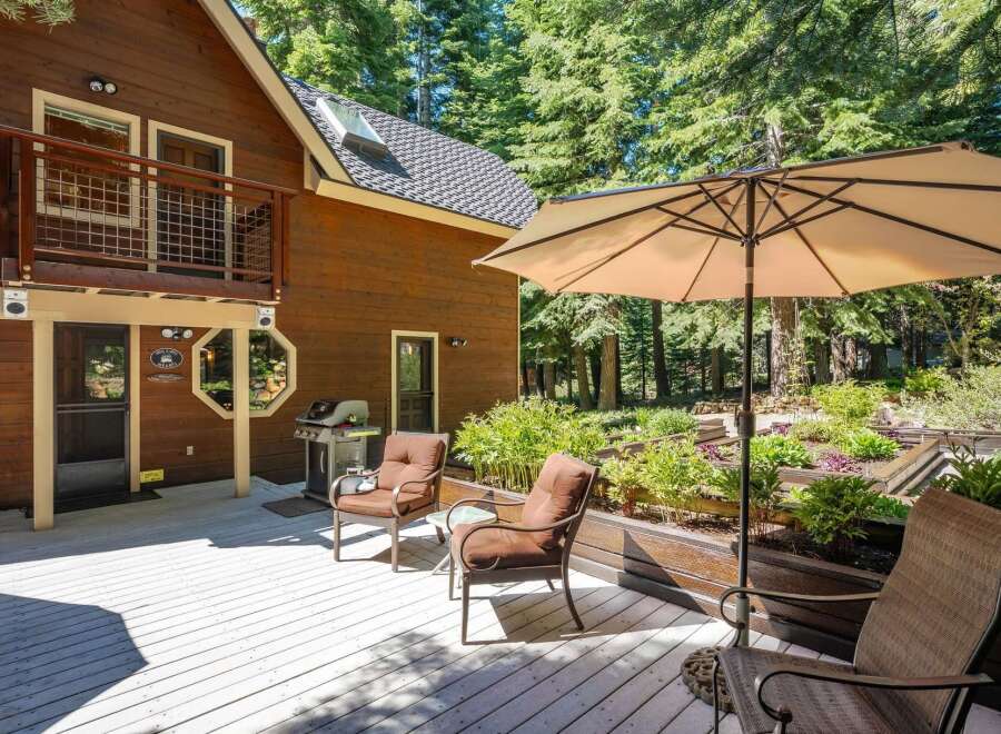 Enjoy outdoor living on this spacious wooden deck, perfect for entertaining or relaxing amidst a serene forest setting.