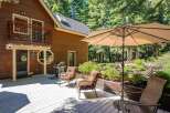 Enjoy outdoor living on this spacious wooden deck, perfect for entertaining or relaxing amidst a serene forest setting.