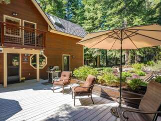 Enjoy outdoor living on this spacious wooden deck, perfect for entertaining or relaxing amidst a serene forest setting.