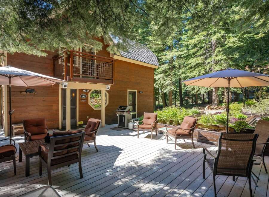Enjoy outdoor living on this spacious wooden deck, perfect for entertaining or relaxing amidst a serene forest setting.
