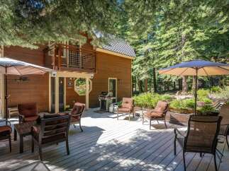 Enjoy outdoor living on this spacious wooden deck, perfect for entertaining or relaxing amidst a serene forest setting.