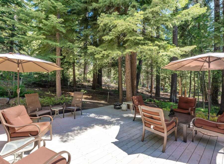 Enjoy the serene mountain lifestyle on this spacious deck, perfect for outdoor entertaining or quiet relaxation amidst towering pine trees.