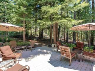 Enjoy the serene mountain lifestyle on this spacious deck, perfect for outdoor entertaining or quiet relaxation amidst towering pine trees.