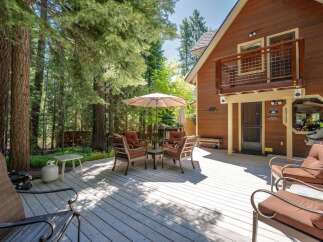 Enjoy outdoor living on this spacious wooden deck, perfect for entertaining or relaxing amidst a serene forest setting.
