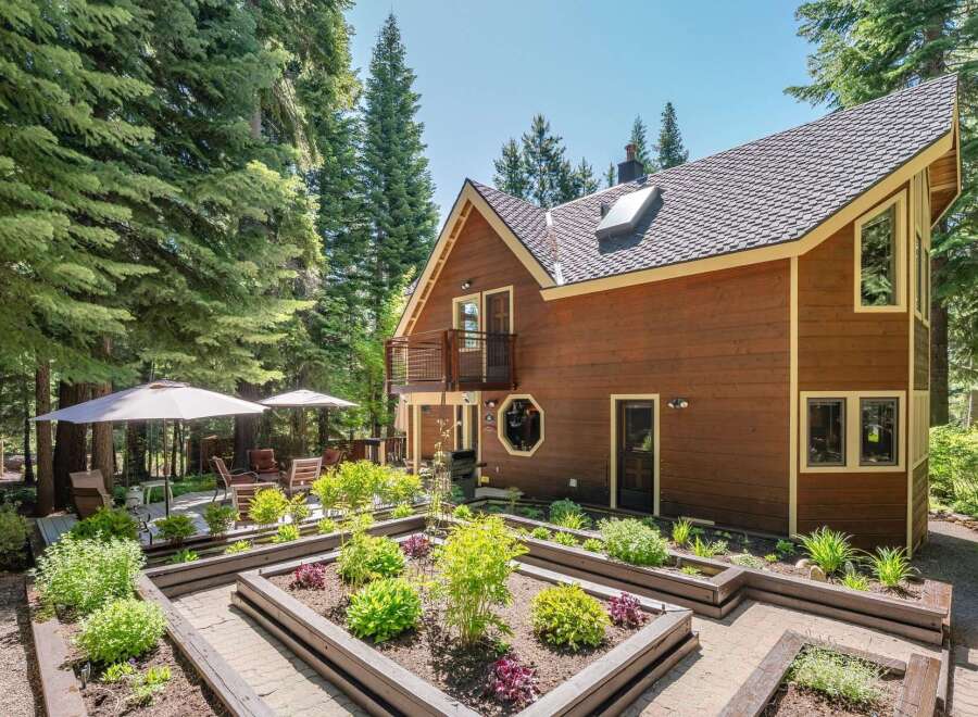 Discover this charming wooden home nestled amongst tall evergreen trees, offering a serene and private retreat.