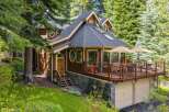 Nestled amidst lush greenery, this charming wooden home offers a serene retreat with its expansive deck perfect for outdoor entertaining.