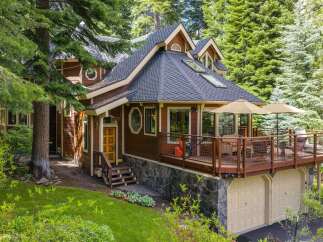 Nestled amidst lush greenery, this charming wooden home offers a serene retreat with its expansive deck perfect for outdoor entertaining.
