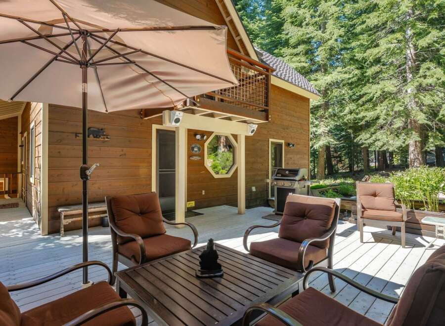 Enjoy outdoor living on this spacious wooden deck, perfect for entertaining or relaxing amidst the serene forest setting.