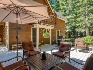 Enjoy outdoor living on this spacious wooden deck, perfect for entertaining or relaxing amidst the serene forest setting.