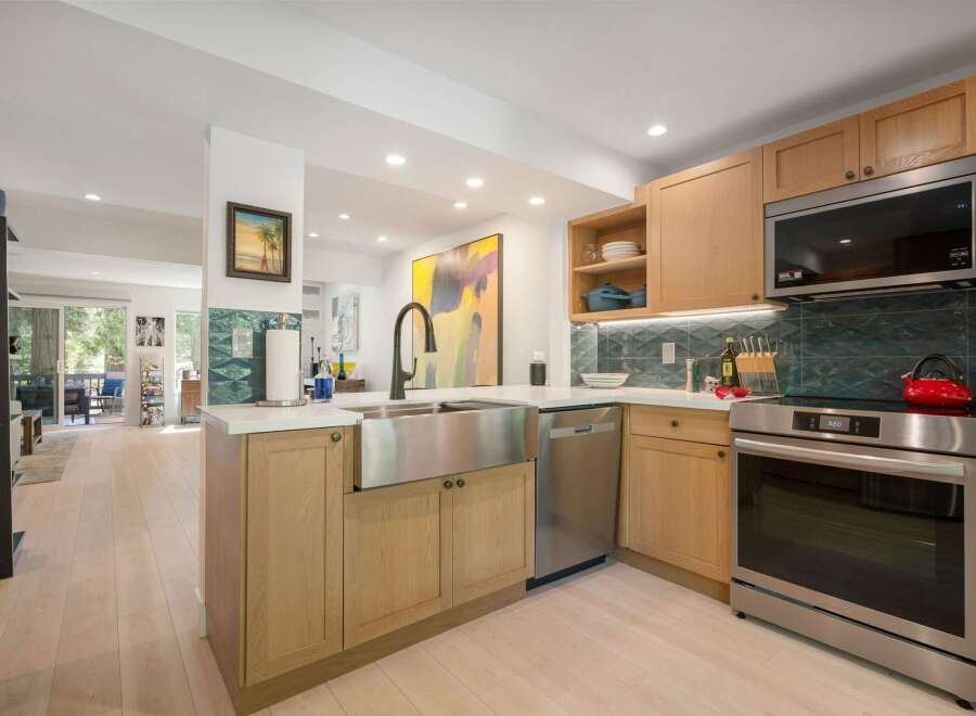Experience modern living in this beautifully updated kitchen, featuring a sleek stainless steel farmhouse sink and a striking geometric tile backsplash.