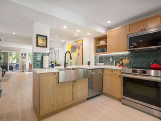 Experience modern living in this beautifully updated kitchen, featuring a sleek stainless steel farmhouse sink and a striking geometric tile backsplash.