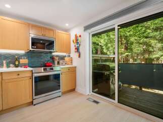 This modern kitchen features sleek, light wood cabinetry and a stylish geometric tile backsplash.