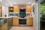 Discover this modern kitchen featuring sleek, light wood cabinetry and a striking geometric backsplash.