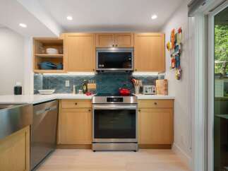 Discover this modern kitchen featuring sleek, light wood cabinetry and a striking geometric backsplash.