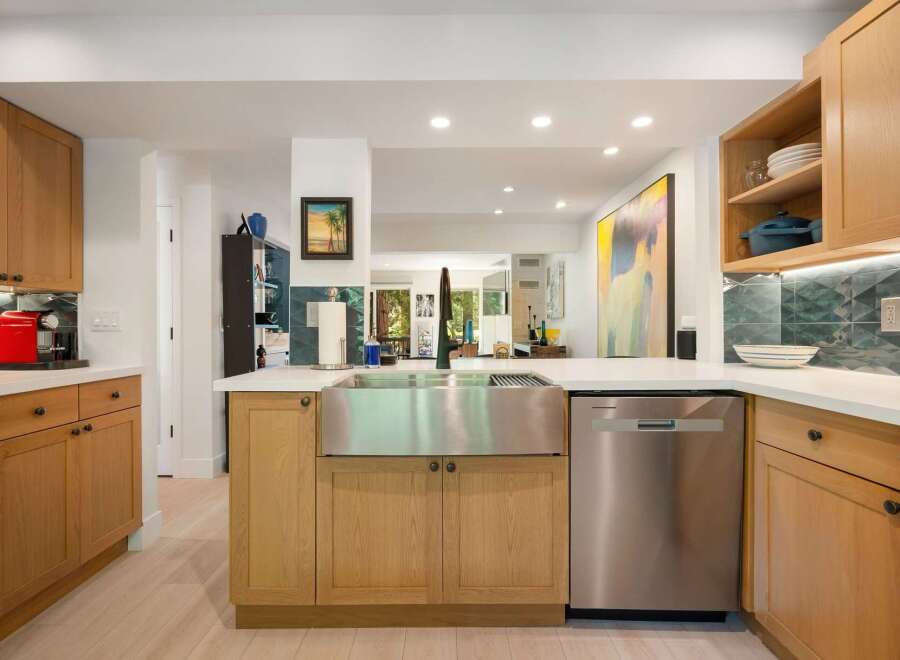 This modern kitchen boasts sleek, light wood cabinetry and a large stainless steel farmhouse sink, perfect for any home chef.