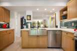 This modern kitchen boasts sleek, light wood cabinetry and a large stainless steel farmhouse sink, perfect for any home chef.