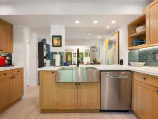 This modern kitchen boasts sleek, light wood cabinetry and a large stainless steel farmhouse sink, perfect for any home chef.