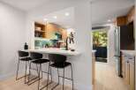 This modern kitchen features a sleek white breakfast bar with black bar stools, perfect for casual dining.