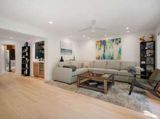 Experience modern living in this spacious open-concept living area, featuring a comfortable sectional sofa, a stylish coffee table, and vibrant abstract art.