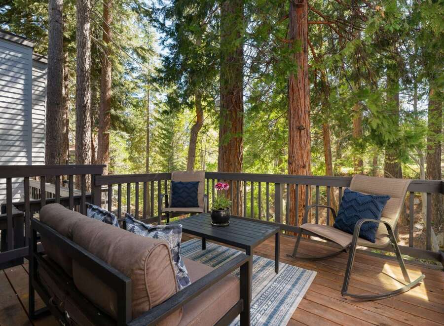 Enjoy the serene mountain lifestyle on this charming deck, perfect for relaxing amidst towering trees.