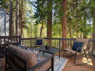 Enjoy the serene mountain lifestyle on this charming deck, perfect for relaxing amidst towering trees.