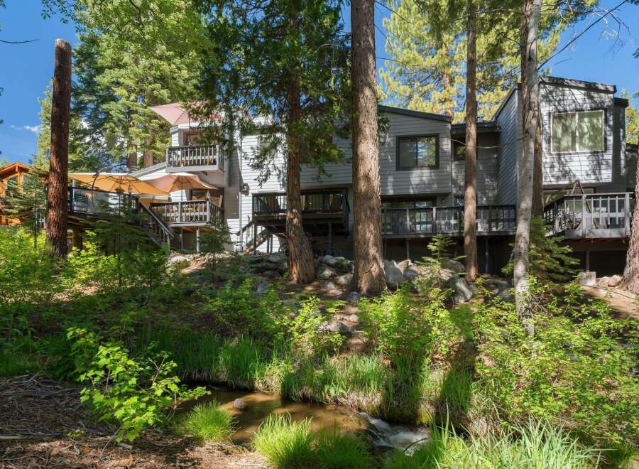 Nestled amongst towering trees, this property offers a serene retreat with multiple levels of outdoor living space.