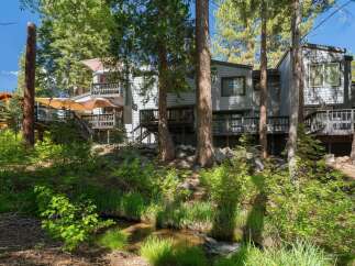 Nestled amongst towering trees, this property offers a serene retreat with multiple levels of outdoor living space.