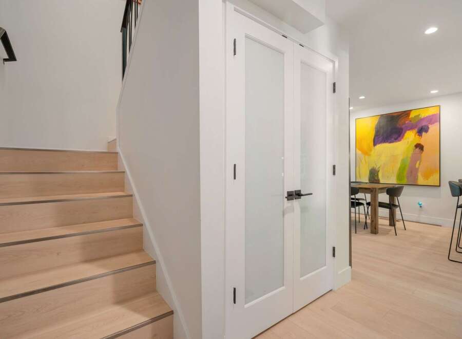Step into modern elegance with this stunning interior featuring a sleek staircase and chic double doors leading to a vibrant dining area.