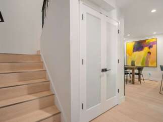 Step into modern elegance with this stunning interior featuring a sleek staircase and chic double doors leading to a vibrant dining area.