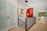 This hallway features a modern staircase with a black metal railing, leading to a bright and airy upper level.