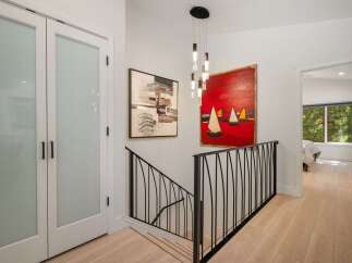 This hallway features a modern staircase with a black metal railing, leading to a bright and airy upper level.