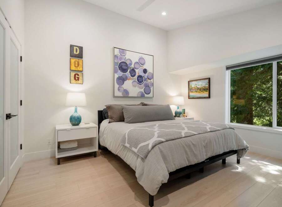 This inviting bedroom features a comfortable king-size bed adorned with plush grey bedding and a decorative throw.