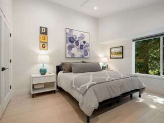 This inviting bedroom features a comfortable king-size bed adorned with plush grey bedding and a decorative throw.