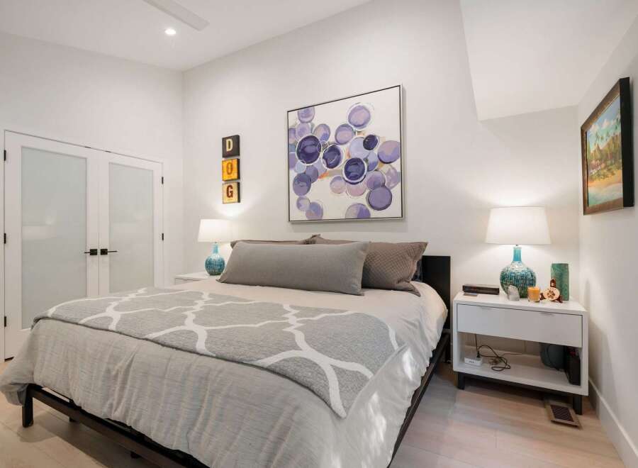 Experience modern comfort in this beautifully appointed bedroom, featuring a plush king-sized bed adorned with elegant grey bedding and a stylish geometric throw.