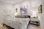 Experience modern comfort in this beautifully appointed bedroom, featuring a plush king-sized bed adorned with elegant grey bedding and a stylish geometric throw.