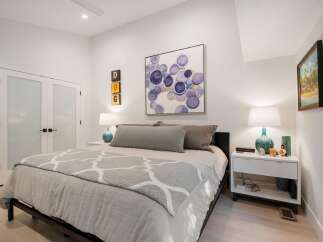 Experience modern comfort in this beautifully appointed bedroom, featuring a plush king-sized bed adorned with elegant grey bedding and a stylish geometric throw.