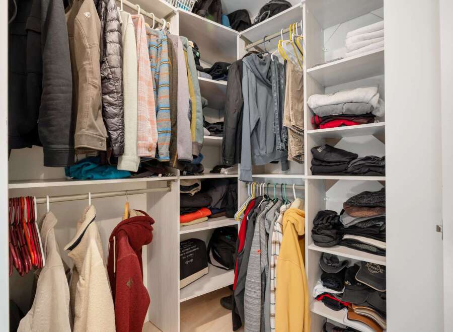 This spacious walk-in closet offers ample storage with multiple shelves and hanging rods, perfect for organizing your wardrobe.