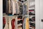 This spacious walk-in closet offers ample storage with multiple shelves and hanging rods, perfect for organizing your wardrobe.