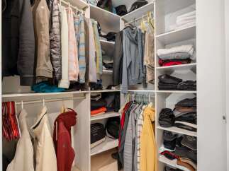 This spacious walk-in closet offers ample storage with multiple shelves and hanging rods, perfect for organizing your wardrobe.