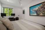 This bedroom features a comfortable bed with striped bedding and a large painting of a coastal scene above it.