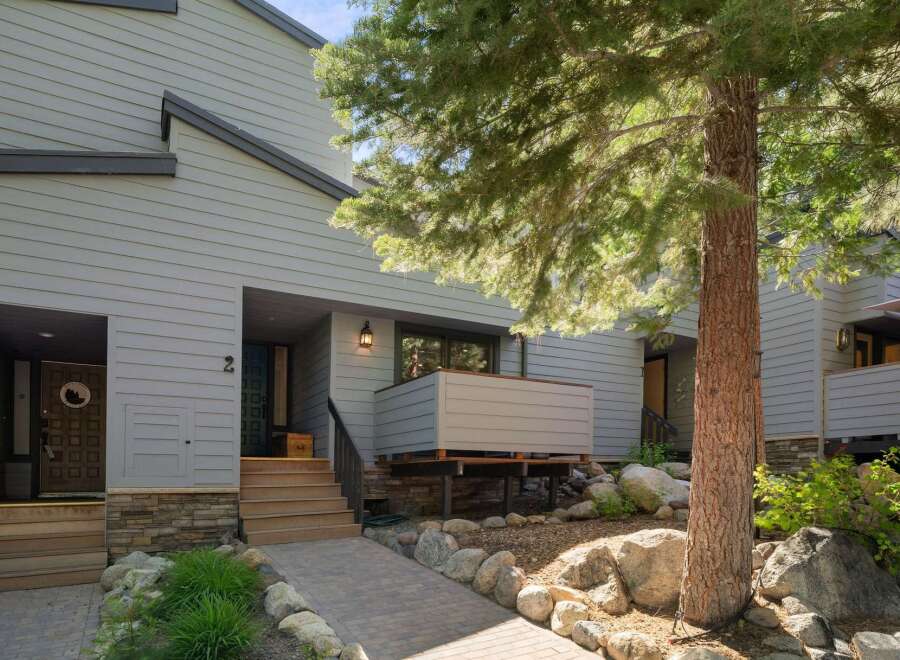 Discover this charming property featuring a welcoming entryway with a stone accent base and a paved walkway leading to the front doors.