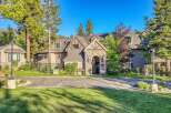 Discover this charming property featuring a stone-arched entryway leading to a multi-story building surrounded by lush greenery and mature trees.