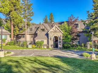 Discover this charming property featuring a stone-arched entryway leading to a multi-story building surrounded by lush greenery and mature trees.