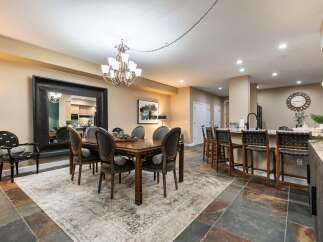 This elegant dining room features a large wooden table with upholstered chairs, complemented by a striking oversized mirror and a modern chandelier.