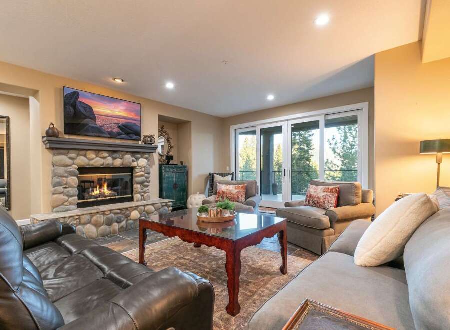 Experience luxurious living in this stunning great room, featuring a magnificent stone fireplace and a large flat-screen TV perfect for cozy evenings.